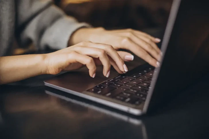 Kobieta pisząca na laptopie – przykład tworzenia treści, które budują przewagę w SEO i zaufanie użytkowników.